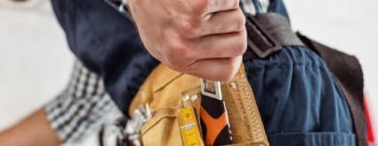 Close-up of a handyman's tool belt with a tape measure and tools