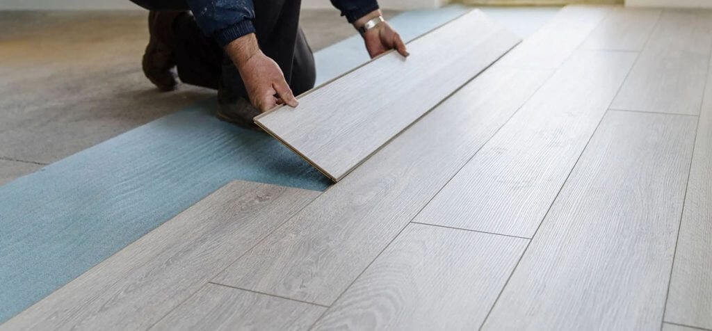 Construction worker installing new laminate flooring in a room