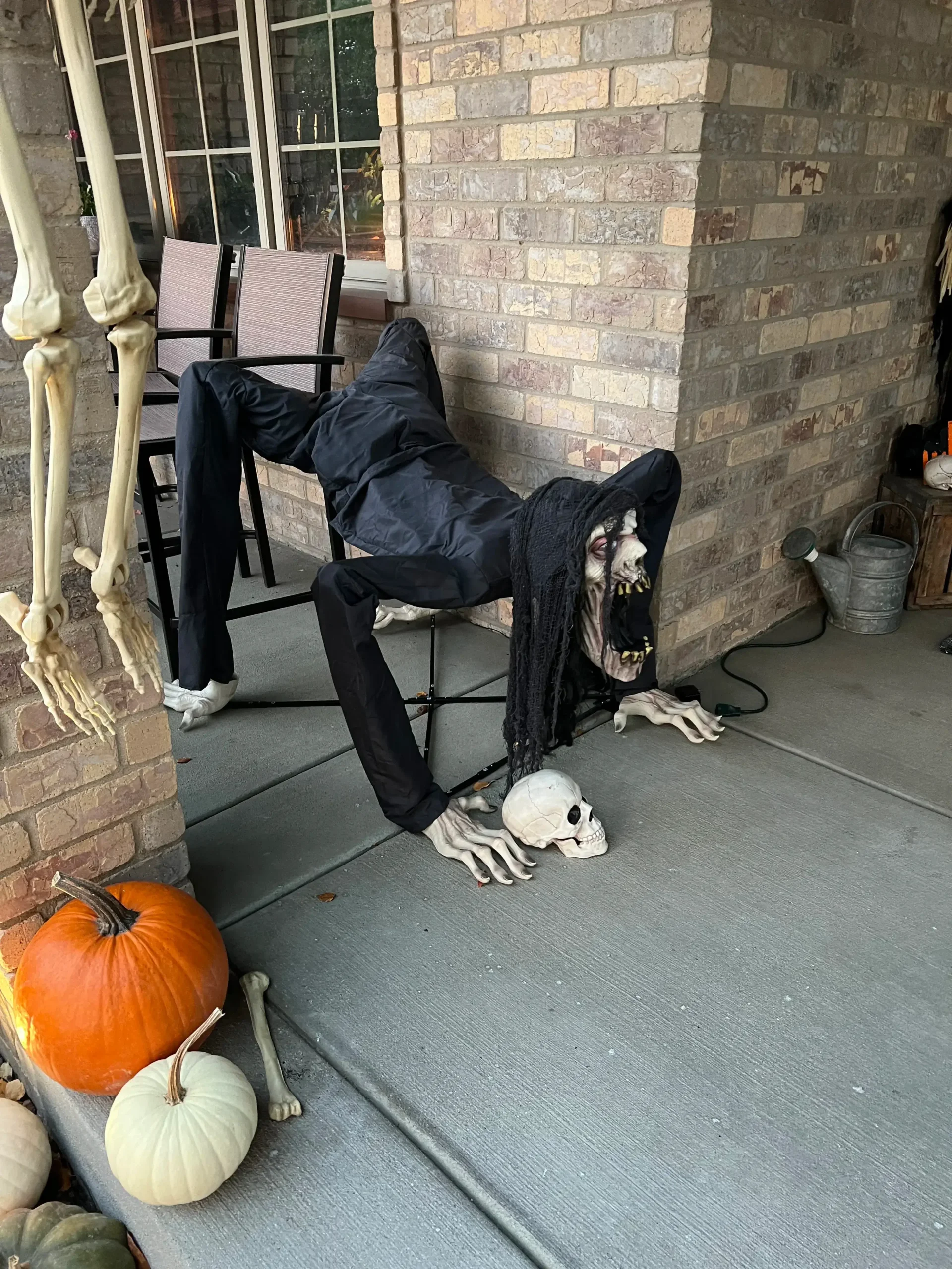 Terrifying contorted monster animatronic with skull and pumpkins on a front porch by Halloween Decorating Service Chicago.
