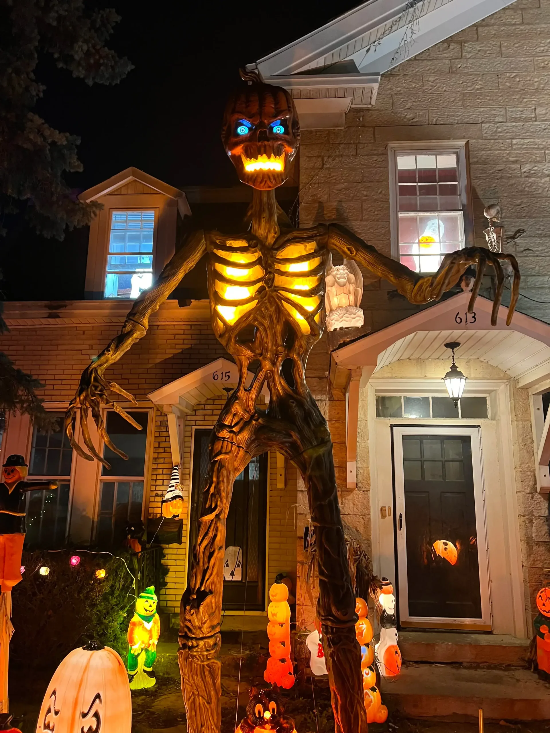 Giant glowing pumpkin-headed skeleton towering over a front yard, installed by a Halloween Decorating Service Chicago.
