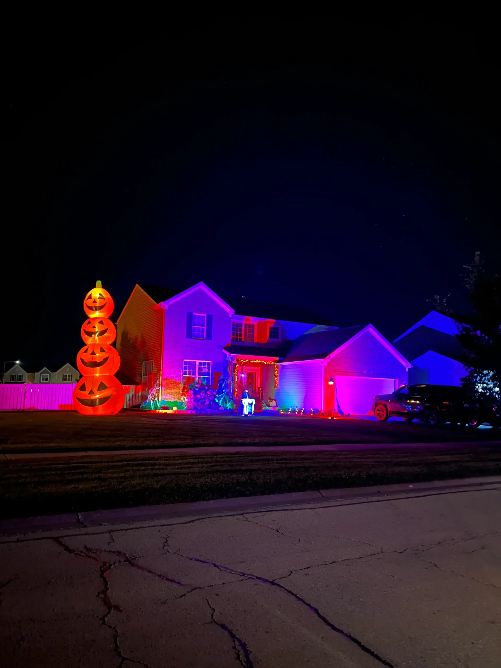 Tall inflatable pumpkin stack and vibrant purple exterior lighting on a residential home by Halloween Decorating Service Chicago.
